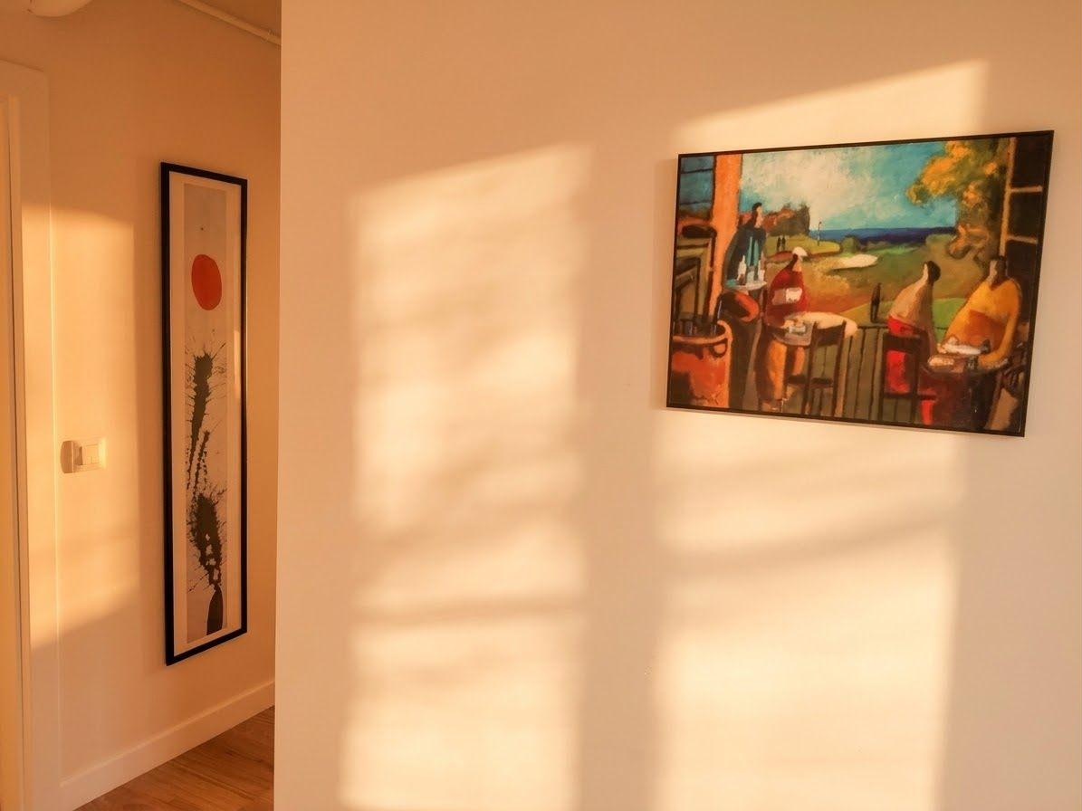 Hallway view toward a built-in wardrobe, two framed prints hung symmetrically, paper lantern pendant