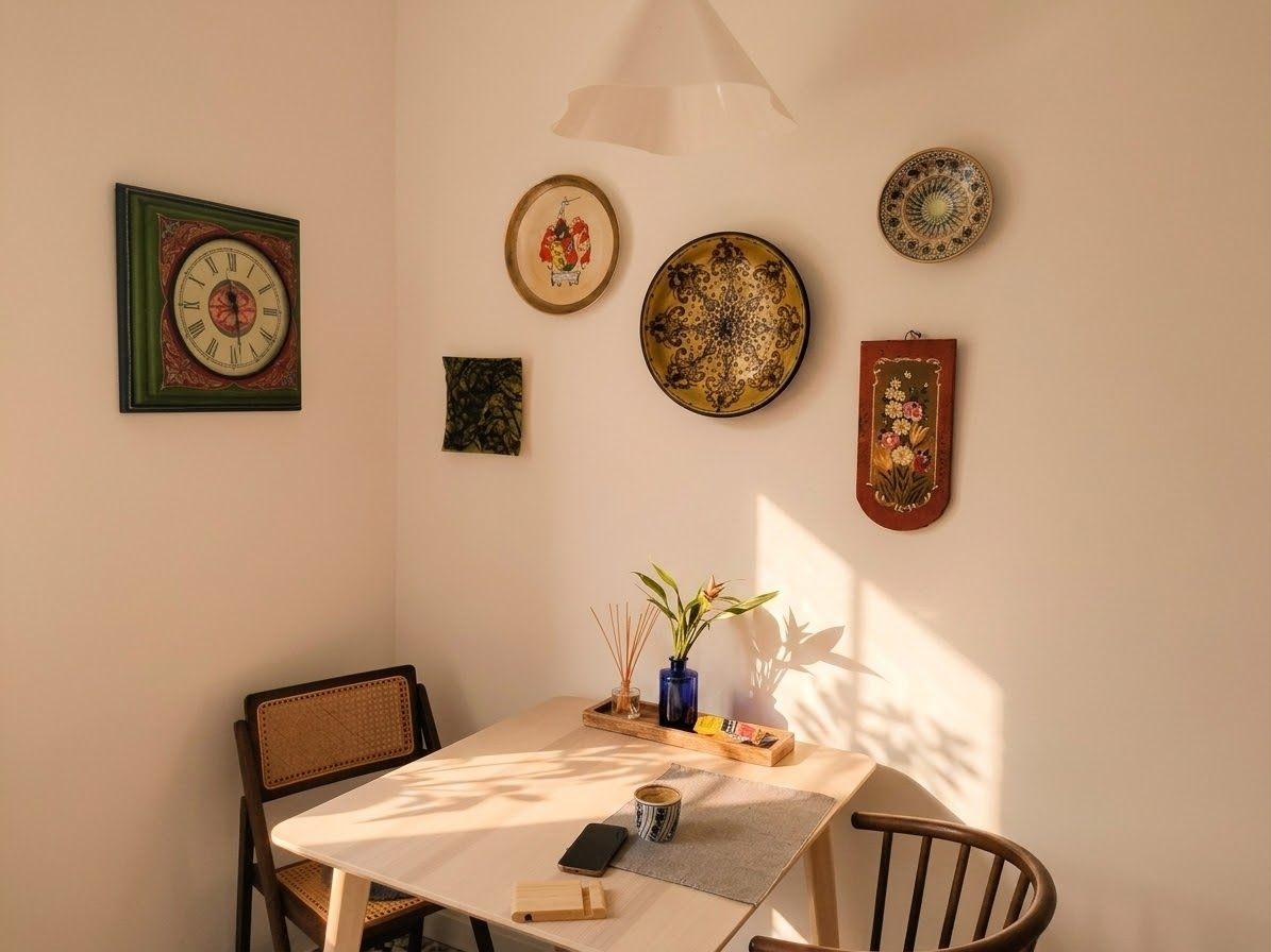 Afternoon light crossing a hallway wall in bars, framed prints receding toward the far end