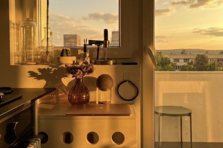 Still life on the circle-cutout cabinet: glass jars, amber vase, wooden sphere, leather loop, plant shadow